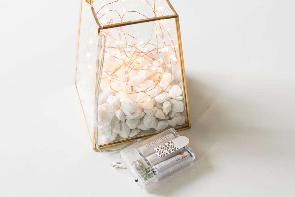 gold terrarium with fairy lights battery pack on a table