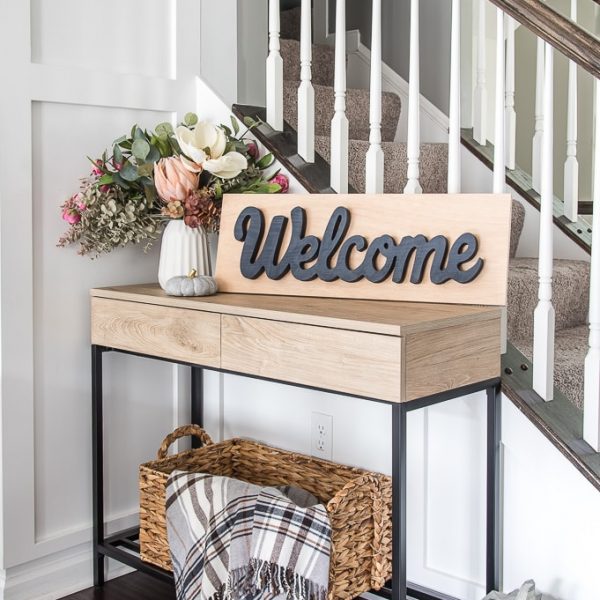 console table with wooden welcome sign and floral arrangement