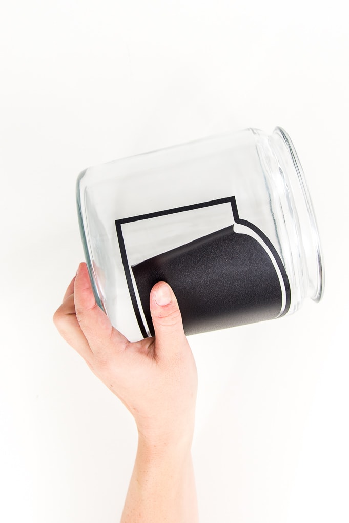 pressing chalkboard vinyl onto glass jar with hand