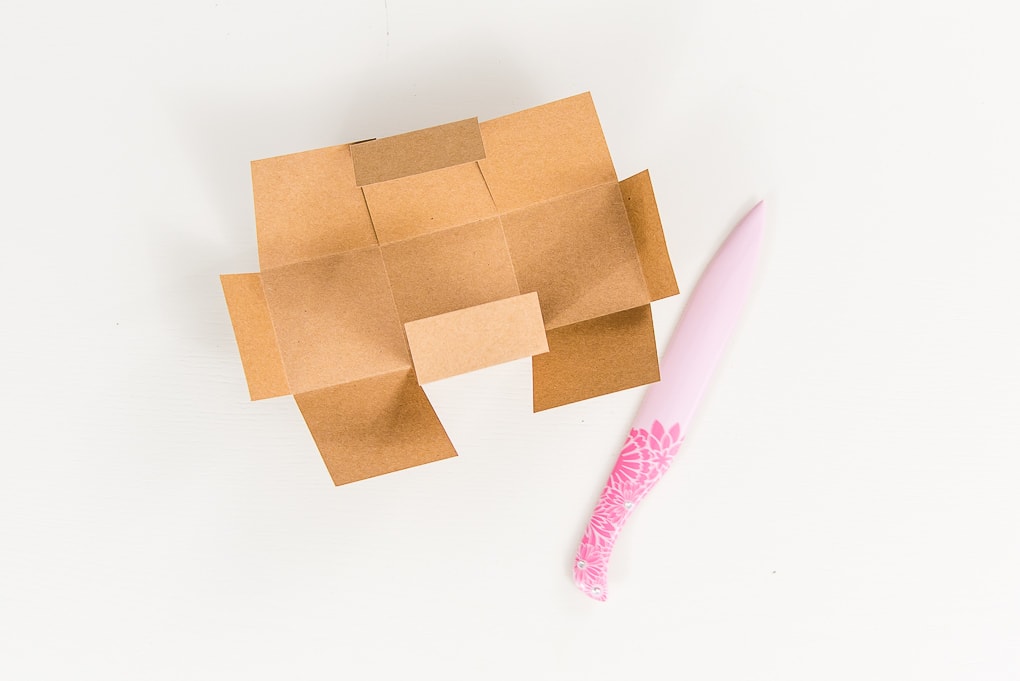 folding a 3D brown paper box with a bone folder