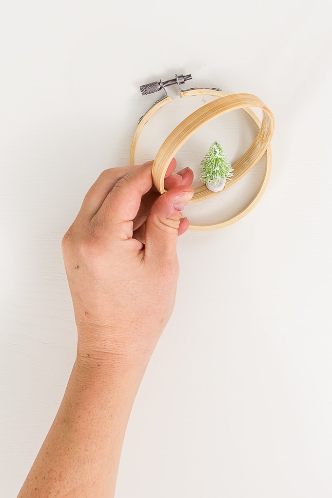 hand holding small embroidery hoop with mini Christmas tree attached