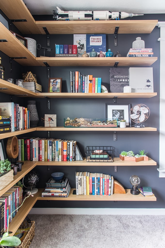 floating industrial shelves with decorations and books in modern masculine home office