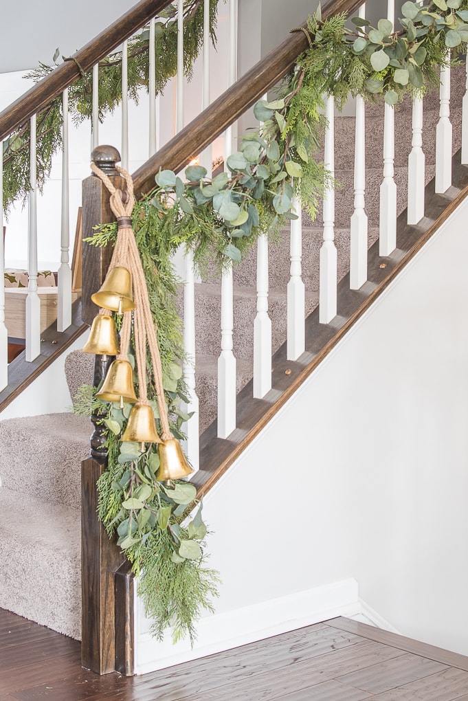 Gold bell Christmas decor on garland on staircase