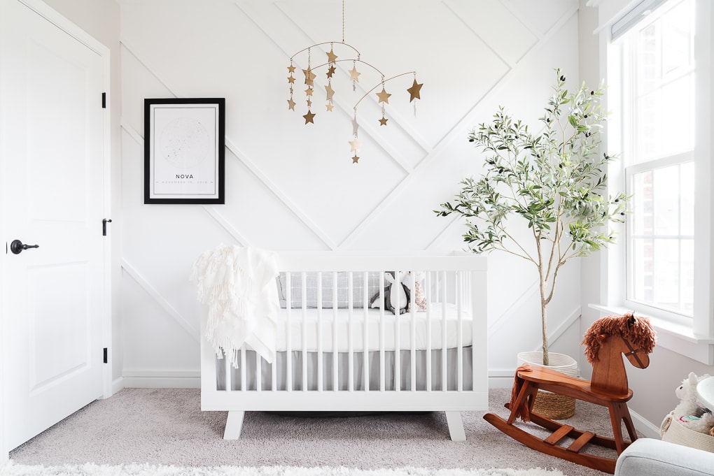 modern neutral nursery with a white crib against a white accent wall and gold accents