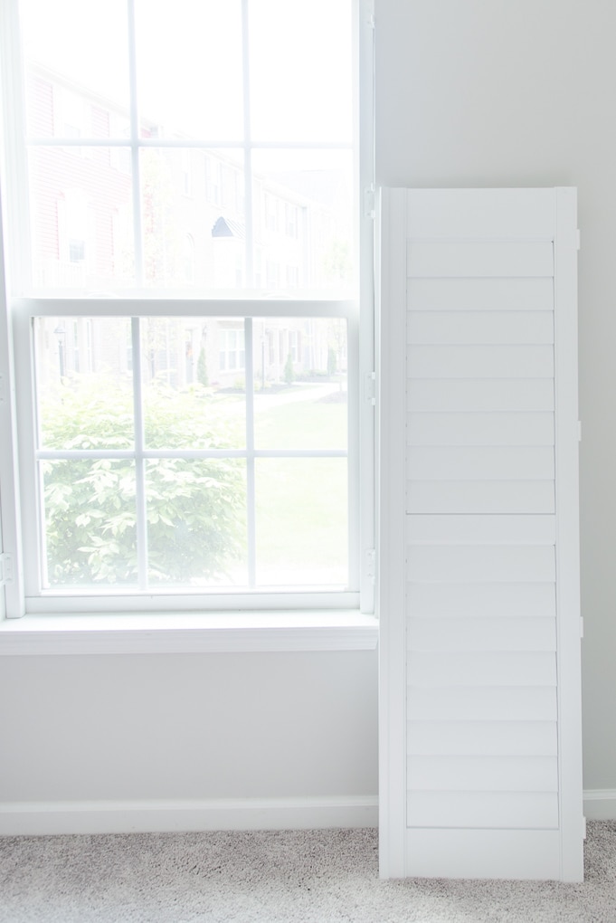 white plantation shutters next to a window before install with louvers closed