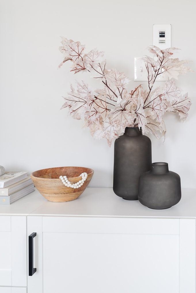 black vases with fall leaves and wooden bowl home decor