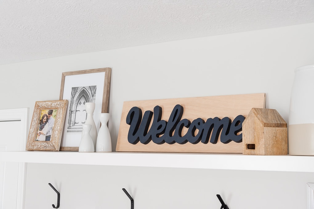 wooden welcome sign and other decor on entryway shelf