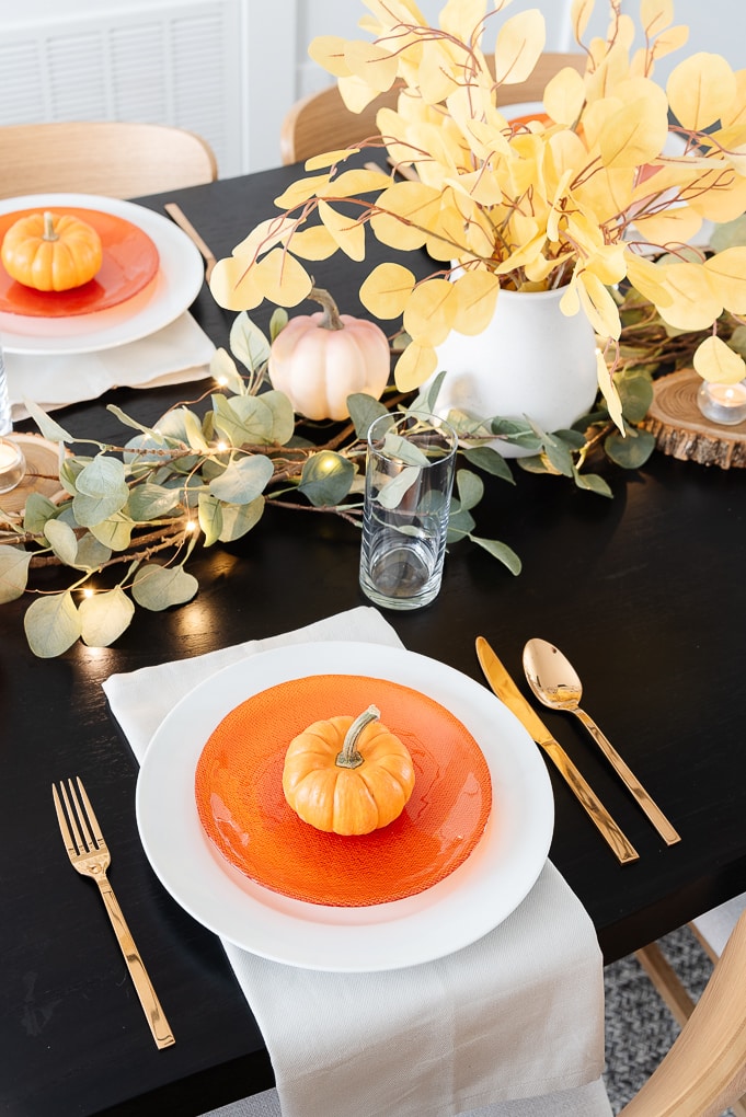 thanksgiving table setting white plate and orange salad plate with mini pumpkin on top