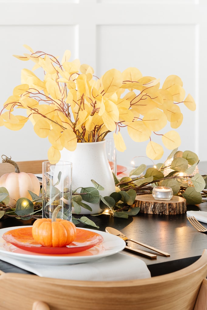 white ceramic vase with yellow eucalyptus stems centerpiece thanksgiving table