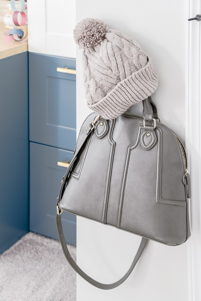 gray purse and brown winter hat on a hook