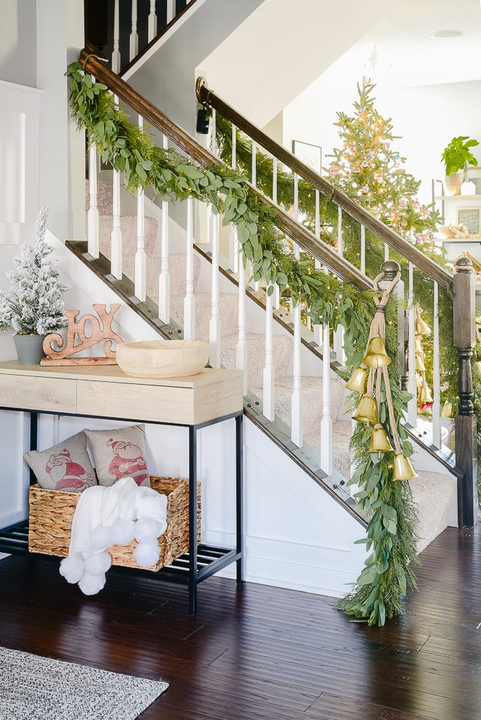 staircase with pine and eucalyptus Christmas garland and golden bells in Christmas dining room