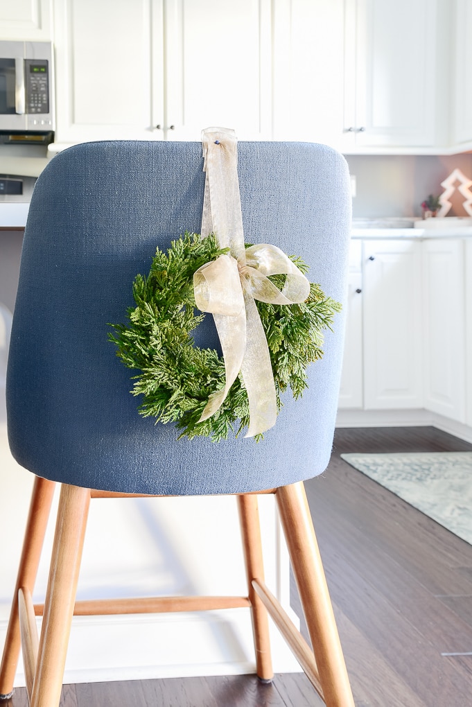 green mini Christmas greenery wreath with bowl attached to blue counter stool
