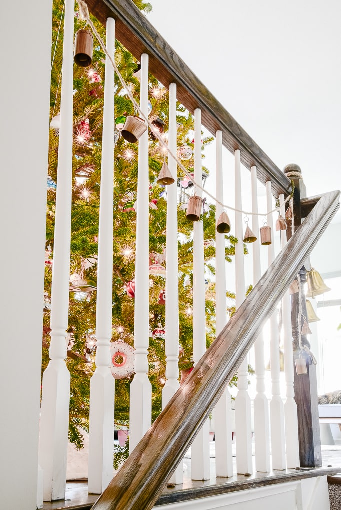 handmade noah bell garland hanging on staircase leading up to Christmas tree