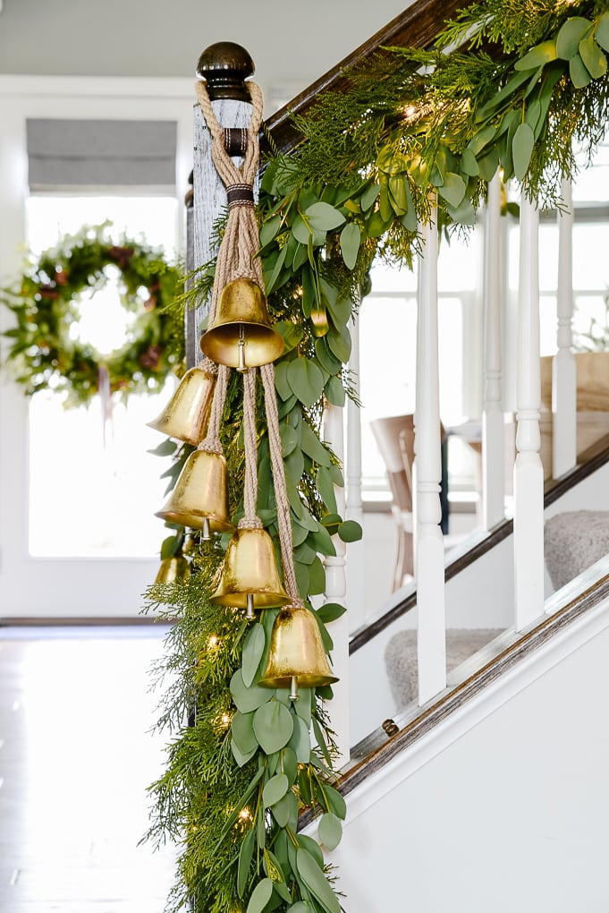 pine and eucalyptus Christmas garland with hanging gold bells on staircase lower section