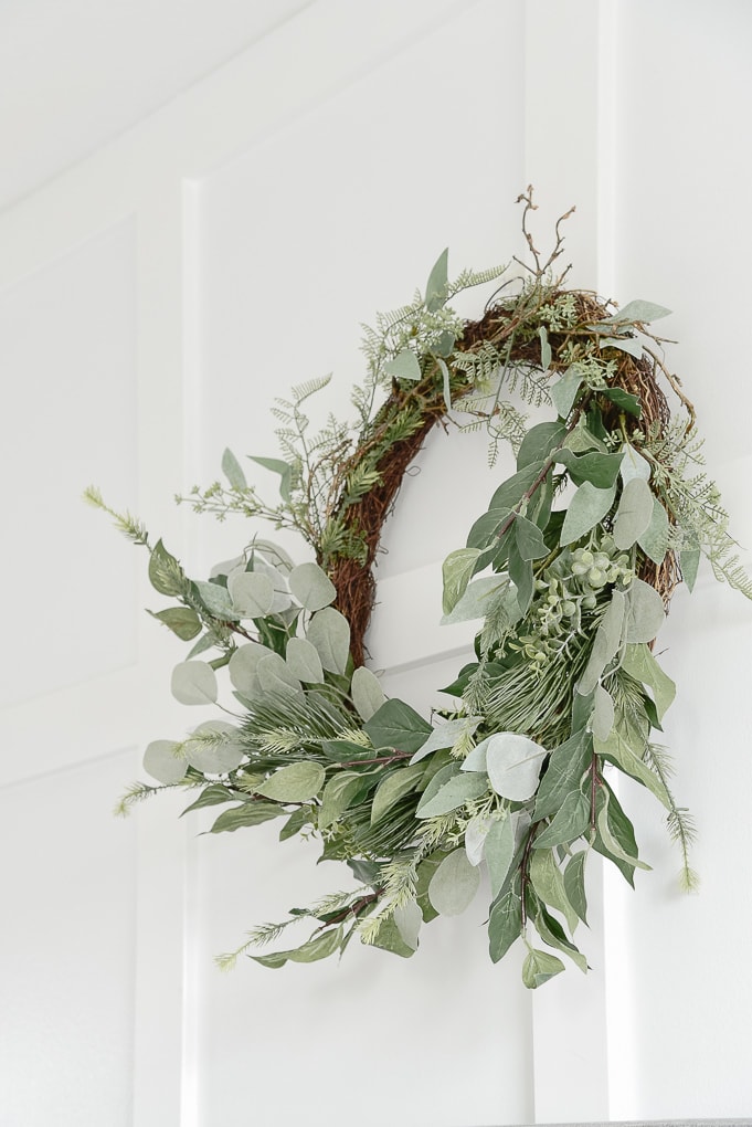 modern greenery and eucalyptus wreath against white board and batten wall