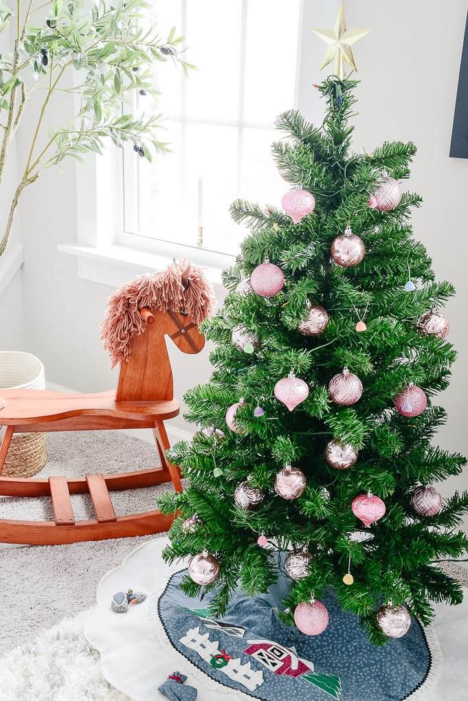 small kids Christmas tree in nursery next to a rocking horse