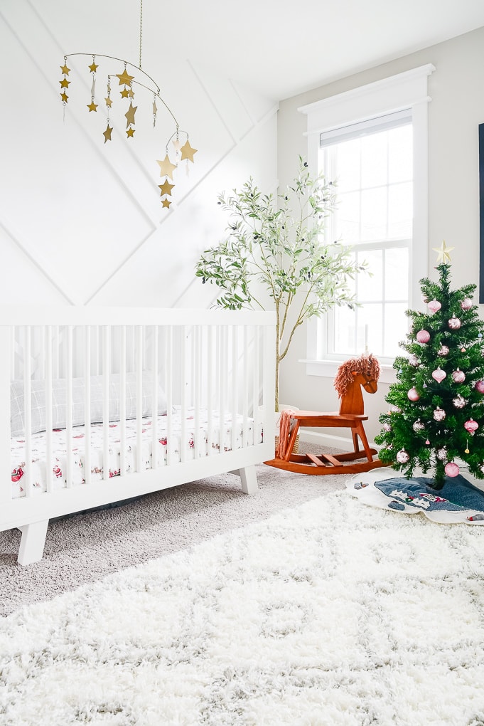 white nursery decorated for christmas with a small tree